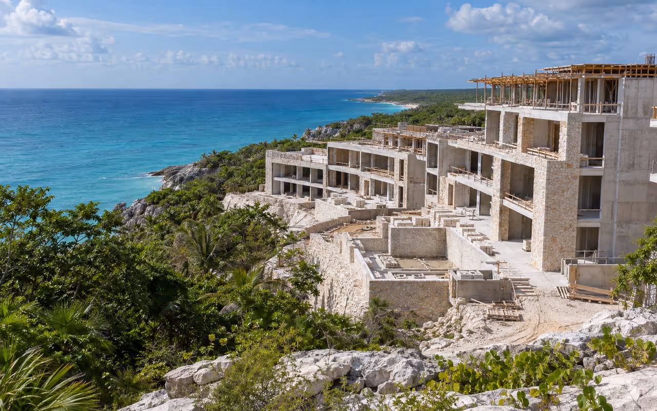 Edificio hotelero en construcción junto al mar Caribe con selva alrededor.